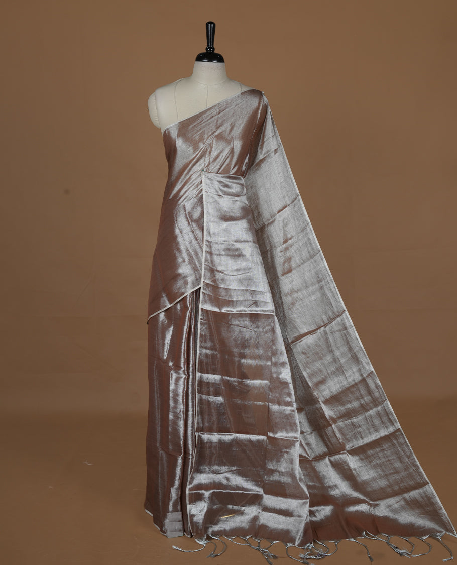 Copper colour semi tissue saree featuring an elegant plain body, designed without a border and comes without a blouse piece.