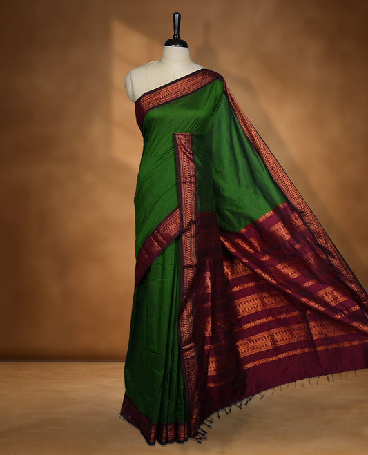 Green colour Kalyani cotton saree featuring a plain elegant body, complemented by a deep maroon border and traditional woven pallu, paired with a matching blouse.