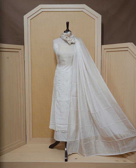 Cream colour Salwar material featuring gold zari Buttas on body & zari worked Neck Portion, paired with matching dupatta & Bottom.