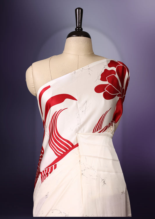 White and red semi modal saree featuring bold floral and abstract patterns across the body and pallu, enhanced with a smooth drape and a matching blouse.