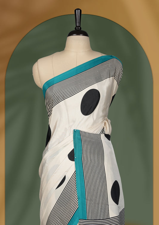 Ivory white colour saree with bold black polka dots and fine stripe detailing, elevated by a vibrant teal border & The striking pallu design adds charm. Lightweight and elegant, paired with matching blouse.