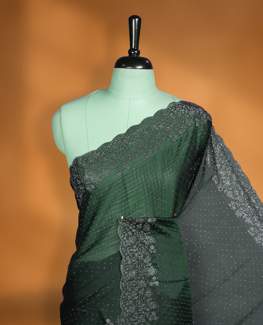 Deep bottle-green chiffon designer saree adorned with delicate white stone work across the body, enhanced with a heavy scalloped stone border and pallu. Paired with a matching stone-detailed blouse.