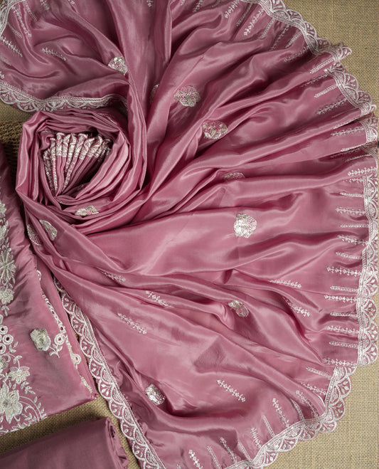 Dusty mauve colour suit material adorned with elegant white thread , cut beads & sequin embroidery, highlighted by a delicate lace border & Paired with a matching embroidered dupatta and plain bottom.