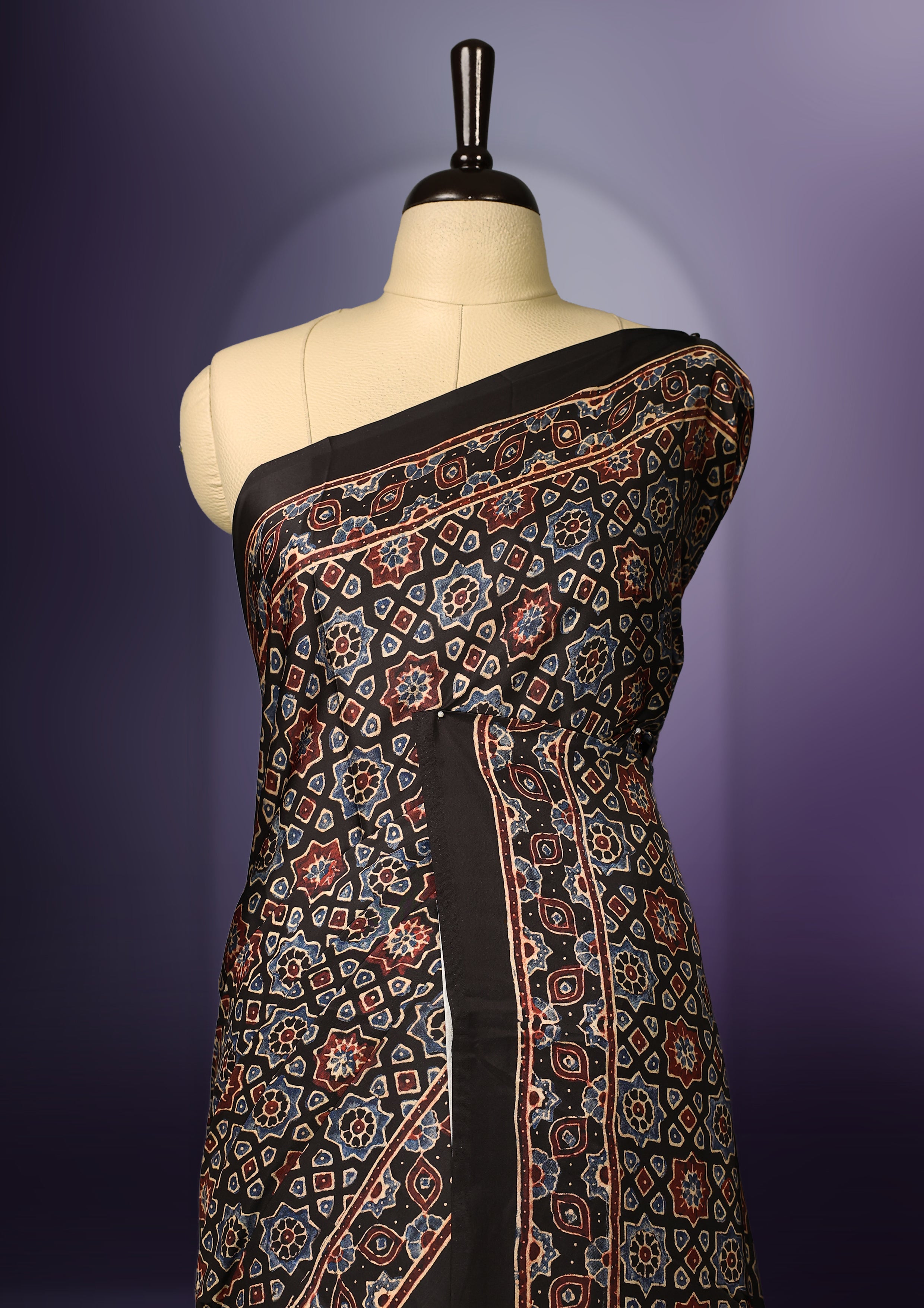 Black colour saree featuring intricate multicolour ethnic prints across the body and pallu, highlighted with a subtle golden border and traditional motifs, paired with a matching blouse.