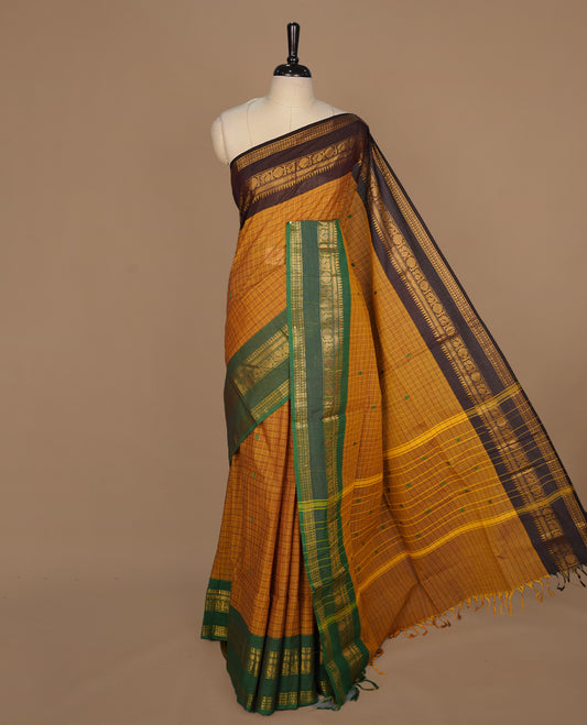 Mustard colour chettinad cotton featuring check pattern on body, complemented by contrast chocolate brown colour with gold zari border, paired with matching blouse piece.