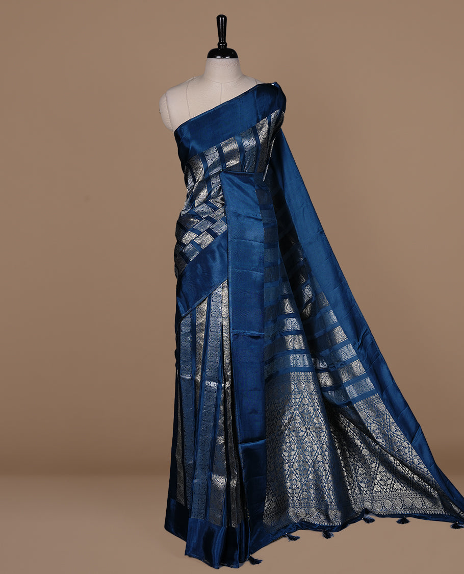 Teal colour banaras crepe saree featuring gold & silver zari design stripes on body, complemented by self colour border, paired with matching blouse piece.
