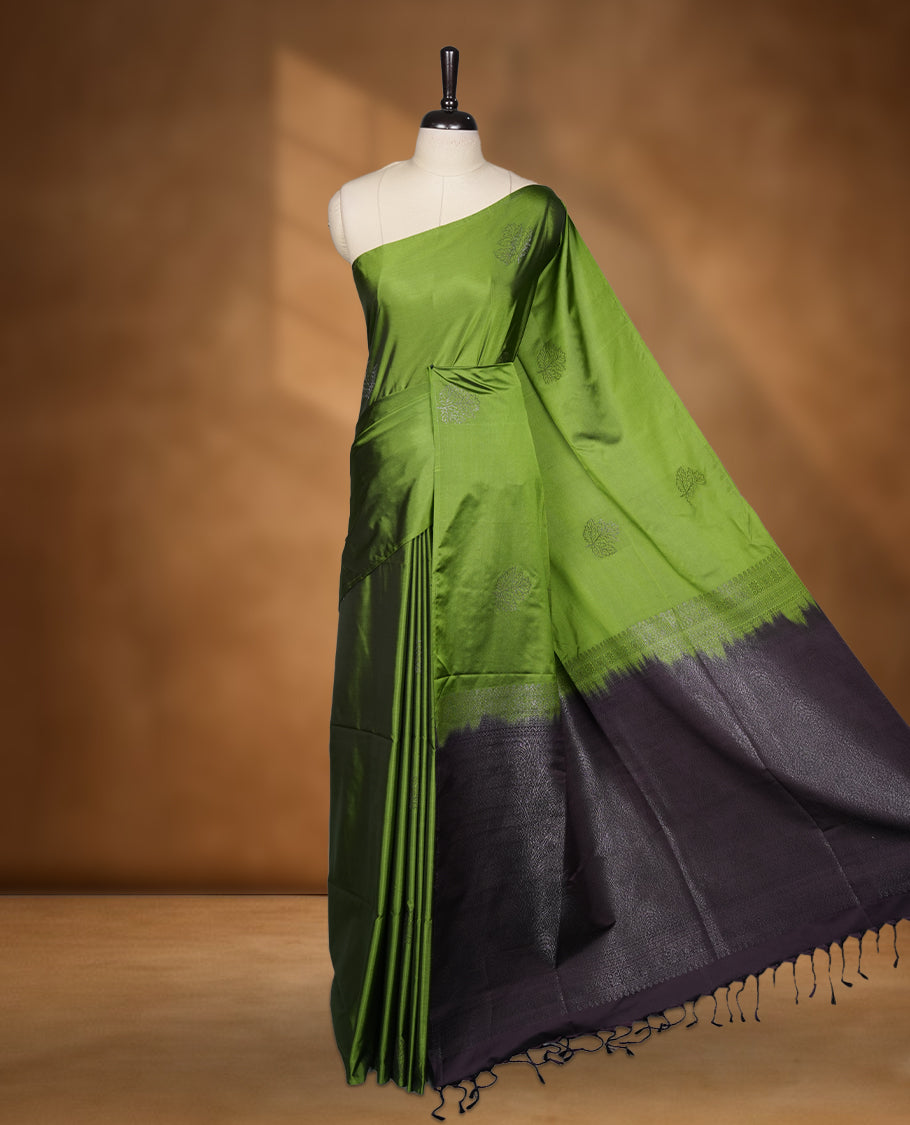 Olive green colour soft silk saree featuring Antique zari motifs on body with Highlighting contrast Navy blue colour pallu and paired with matching blouse piece.