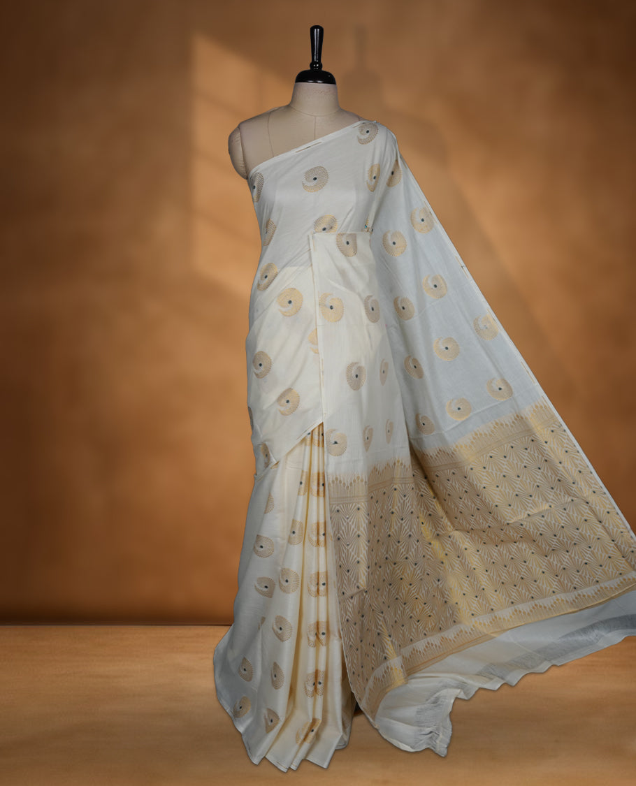 Off white Cotton Kerala saree featuring circular zari motifs, complemented by a rich geometric zari border and traditional pallu, paired with a matching blouse.