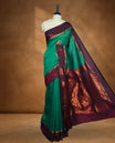 Dark Green colour mixed Kalyani cotton saree with zari motifs on the body, maroon zari border and traditional elephant motif pallu, paired with a matching blouse.