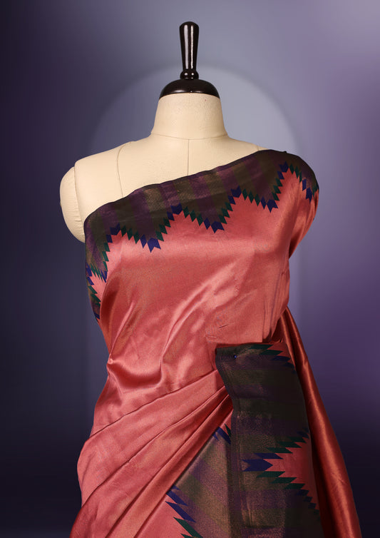 Peach pink saree highlighted with bold black and navy zigzag motifs along the border, complemented by a deep maroon blue pallu with a subtle sheen. Paired with a coordinated blouse piece.