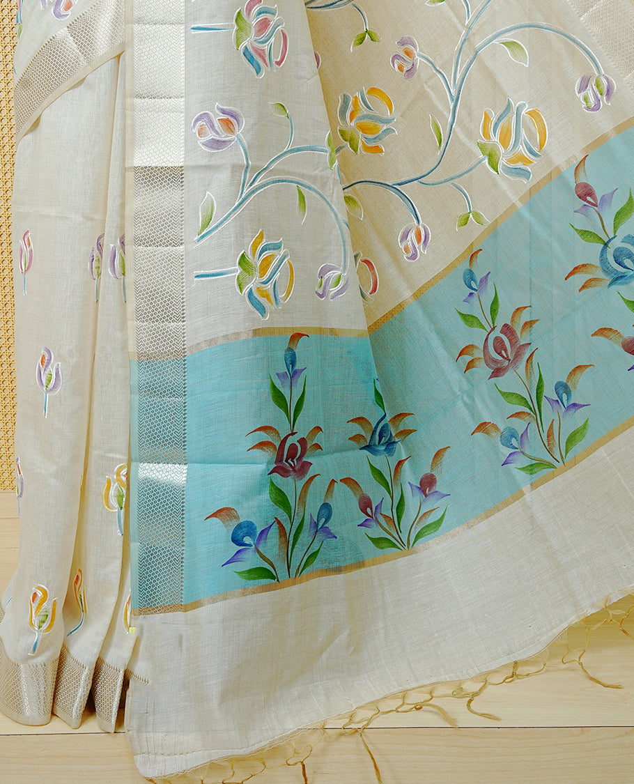 Cream Colour Tissue Kerala Saree Featuring Floral Kodi Threadwork Across The Body, Enhanced With A Light Gold Zari Border And A Light Blue Floral Pallu, Finished With Gold Tassels And A Matching Blouse Piece