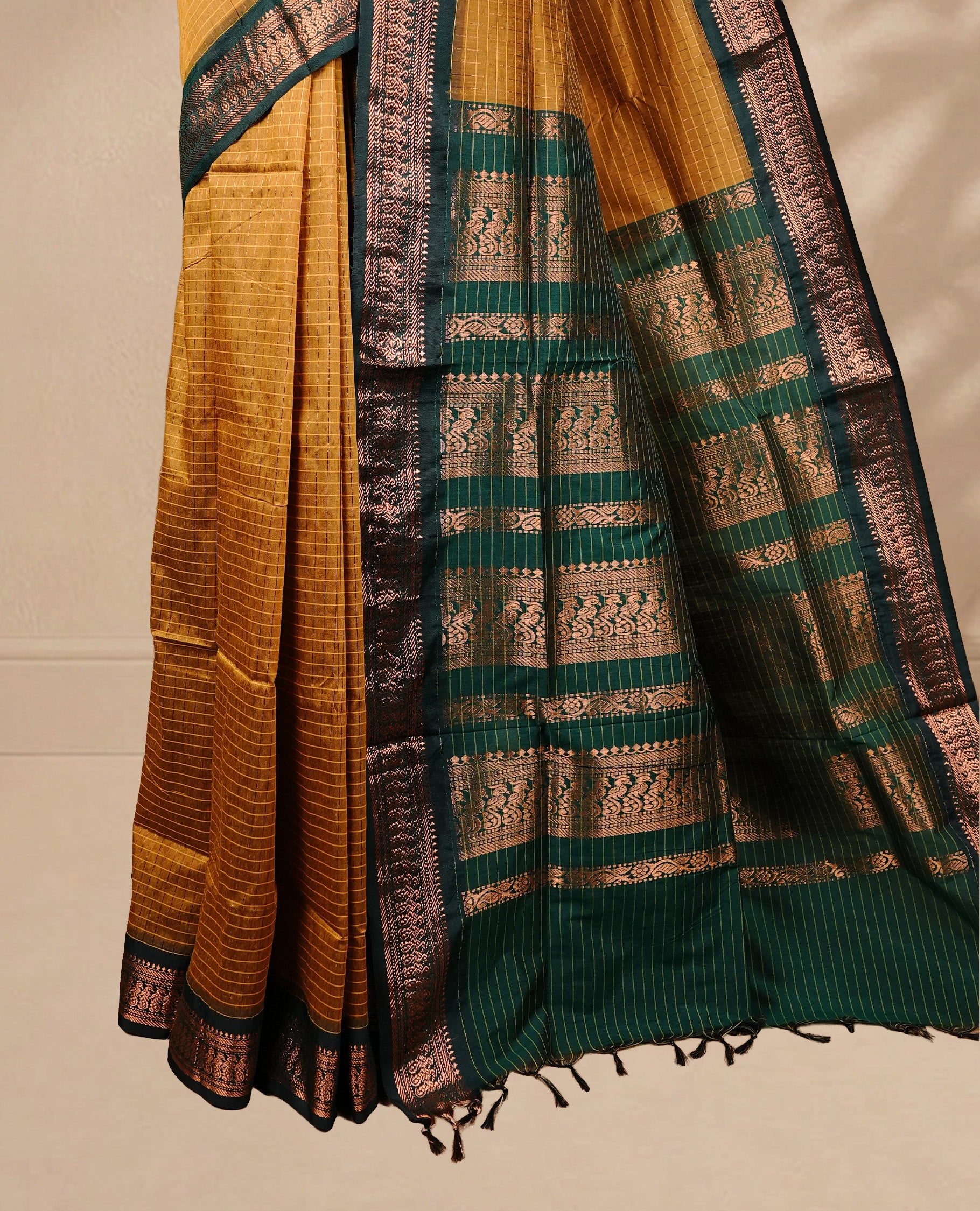 Mustard colour kalyani cotton saree featuring gold zari check pattern on body, complemented by green colour with Antique zari border, paired with matching blouse piece.