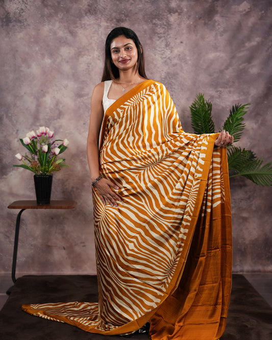 Mustard Yellow Colour satin model saree featuring Zibra print on body. Ajrak & zibra print on pallu with jhumka tassels, comes with contrast plain blouse piece.