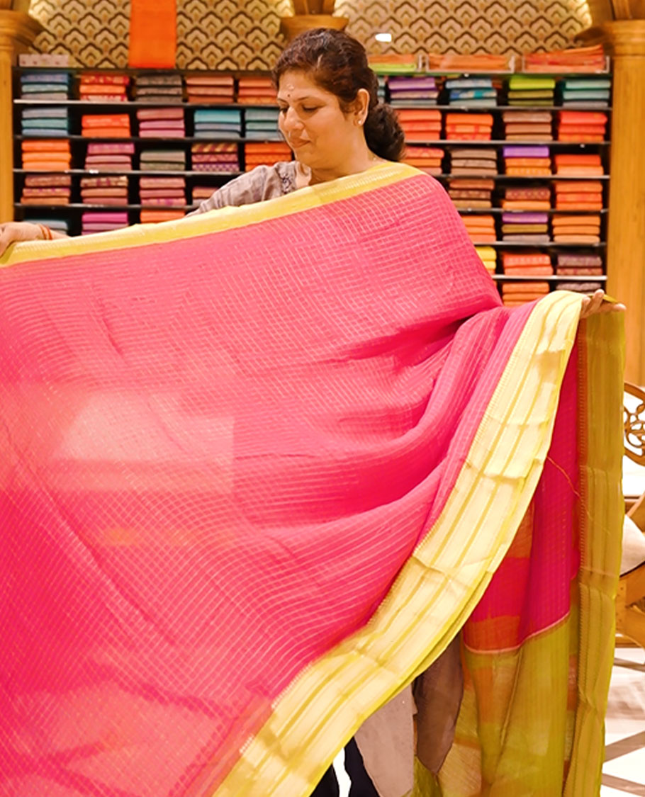 Magenta colour moss chiffon saree featuring gold zari checks designed body, complemented by contrast olive colour zari jacquard border, paired with contrast colour blouse piece.