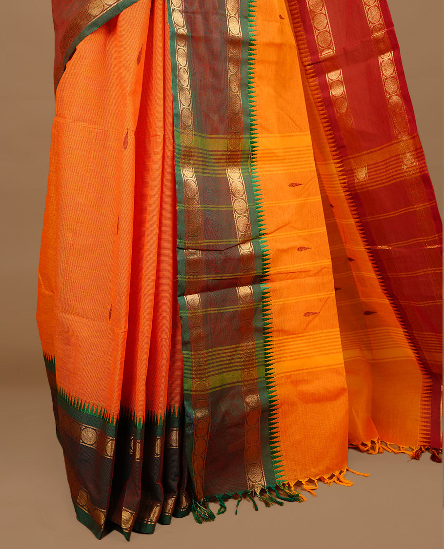 Orange colour chettinad cotton saree featuring motifs on body, complemented by Green colour with zari border, paired with matching blouse piece.