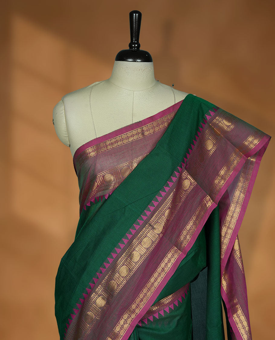 Dark green colour chettinad cotton saree featuring Elegant plain body, contrast Meganta colour border with gold zari chakra and temple border, pallu and paired with matching blouse.