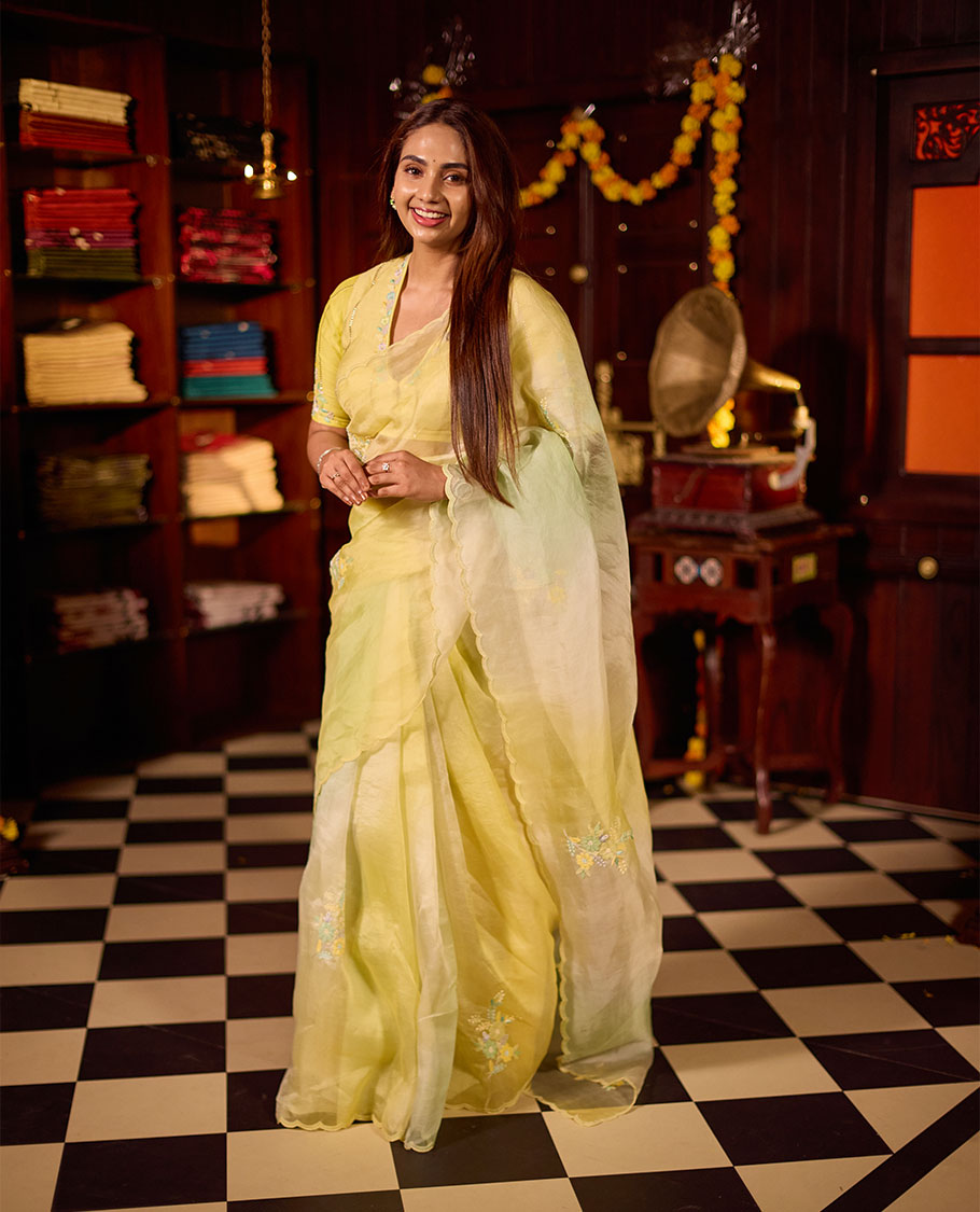 Pastel yellow colour premium organza saree featuring delicate floral hand embroidery with beads and sequins, finished with an elegant scalloped border and paired with a matching embroidered blouse.