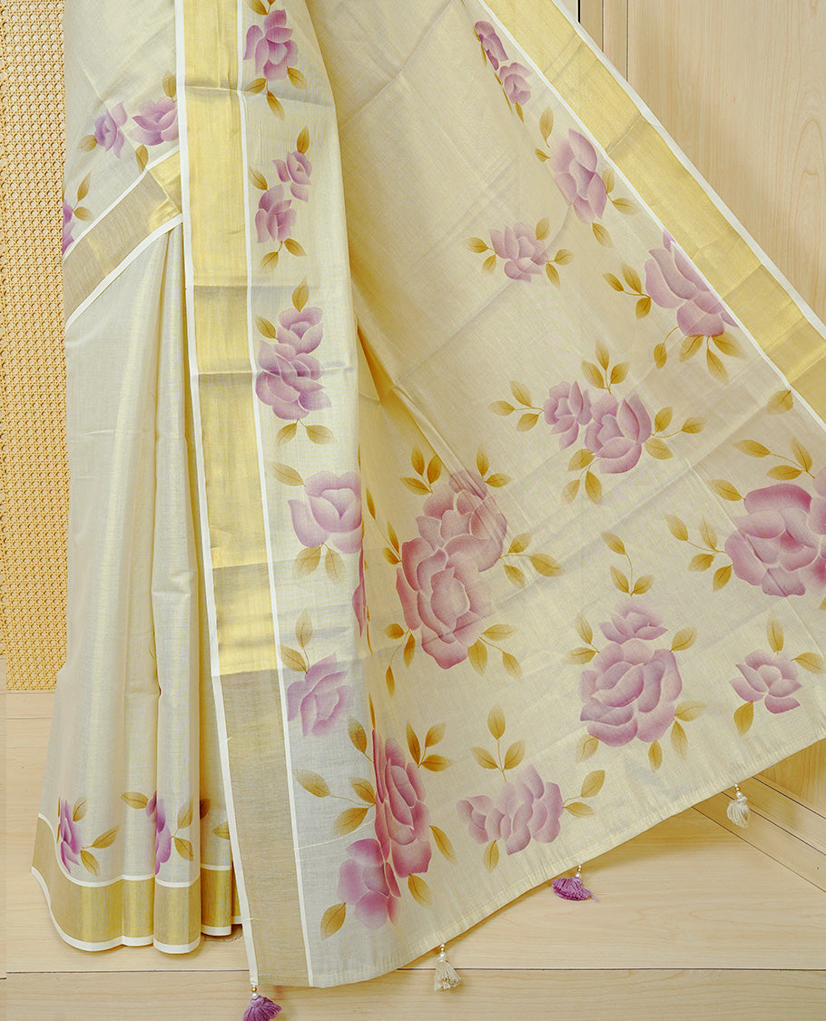 Cream Colour Tissue Kerala Saree Featuring Digital Purple Rose Prints Across The Body, Enhanced With A Gold Zari Border , Finished With Purple & Cream Tassels And A Matching Blouse Piece