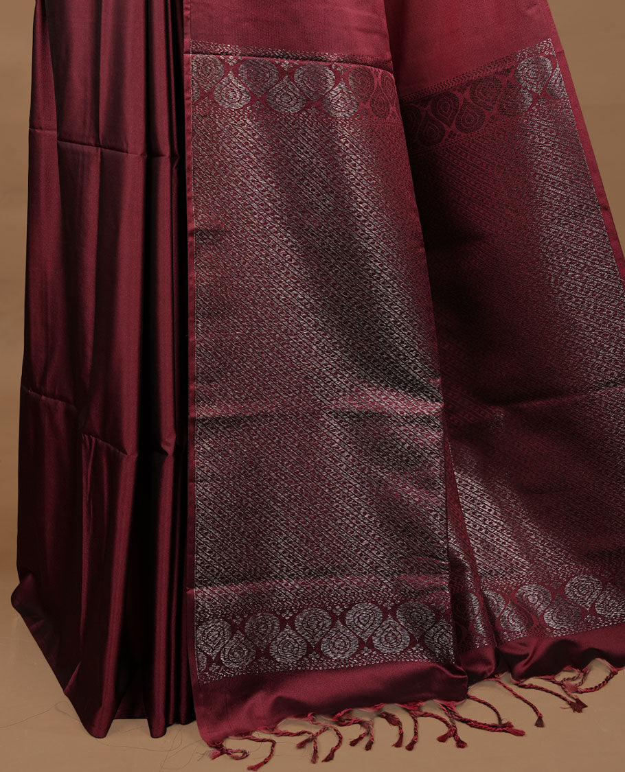 Maroon soft silk saree features a sleek borderless design with intricate antique zari motifs, flowing into a seamless self colored pallu and a matching blouse piece.