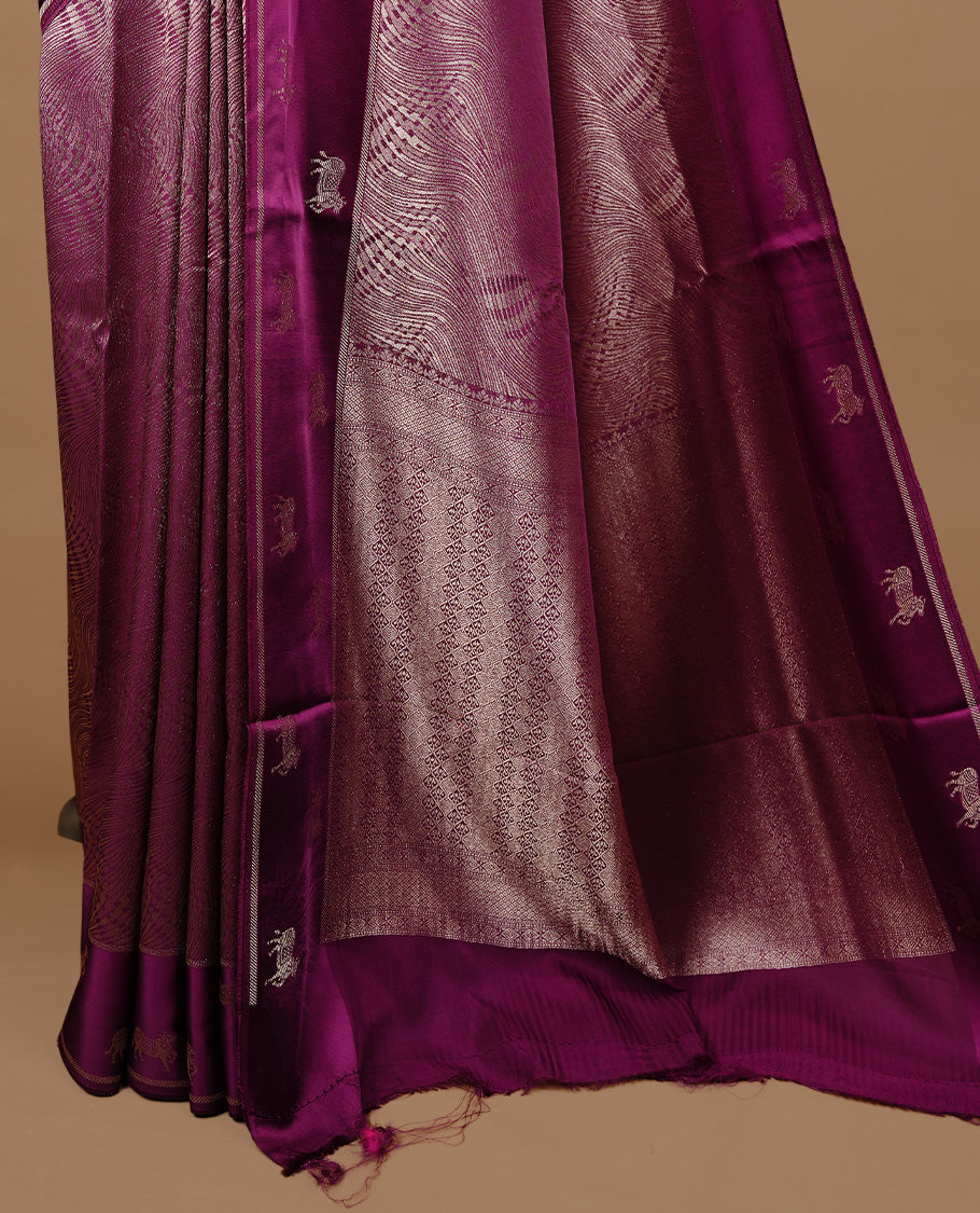 Burgundy colour semi Banaras crepe silk saree featuring an elegant gold zari patterned body, highlighted by a plain border adorned with traditional gold zari cow motifs. Paired with a matching blouse piece.