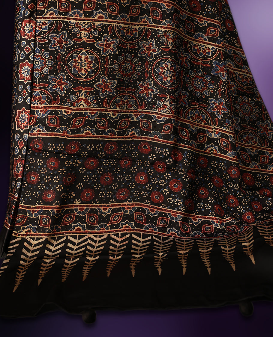Black colour saree featuring intricate multicolour ethnic prints across the body and pallu, highlighted with a subtle golden border and traditional motifs, paired with a matching blouse.