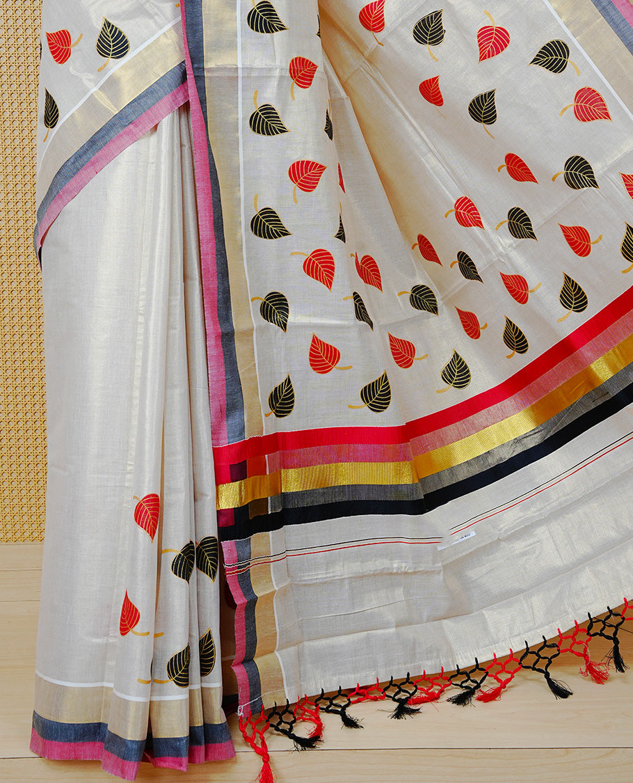 Cream Colour Tissue  Kerala Saree Featuring Red and Black Leaf Prints Across the Body, Enhanced with a Gold Zari, Red and Black Border &  Pallu, Red and Black Tassels, and a Matching Blouse Piece.