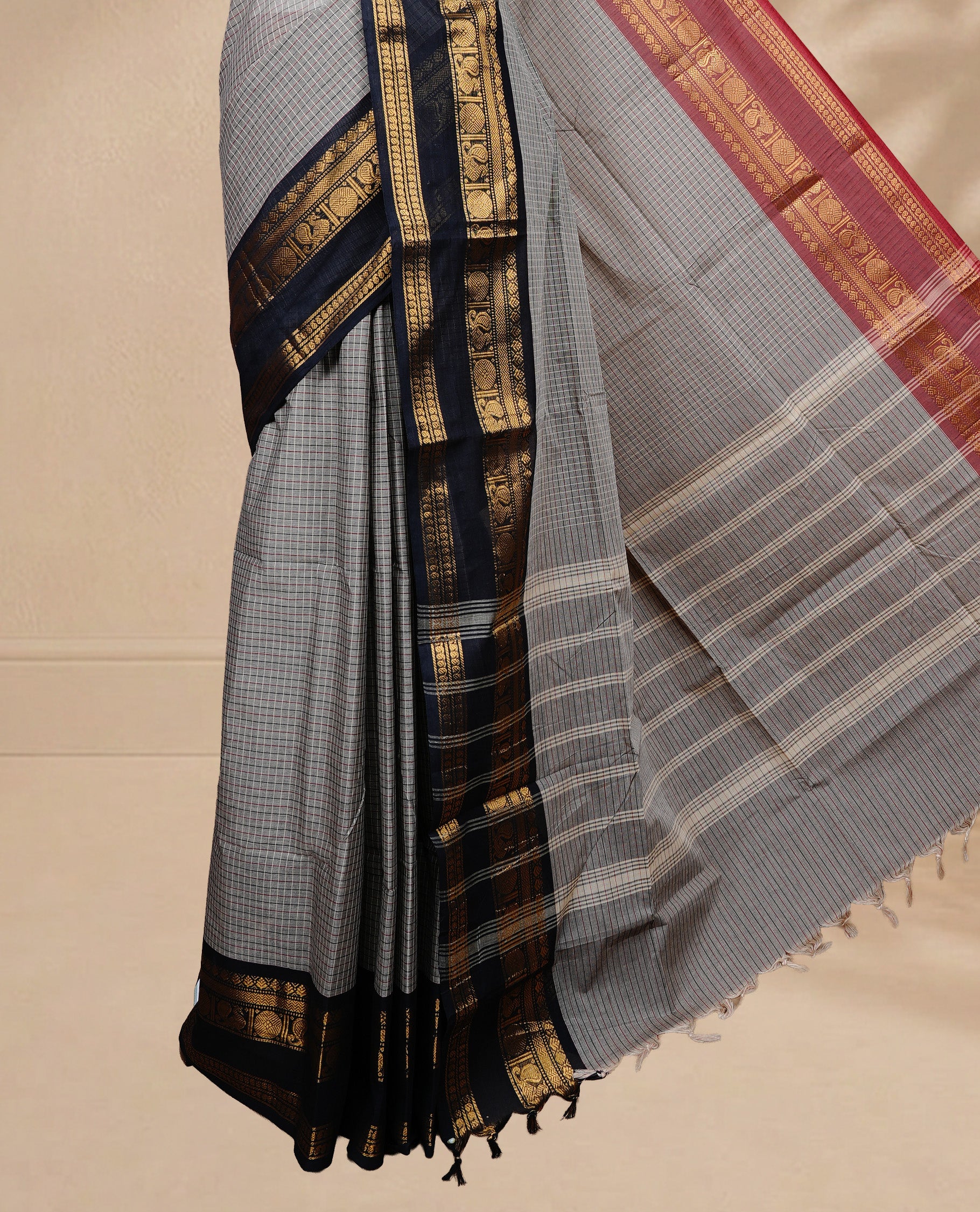 Grey colour chettinad saree featuring Cream colour check pattern on body, complemented by contrast black colour with Gold zari border, paired wih matching blouse piece.