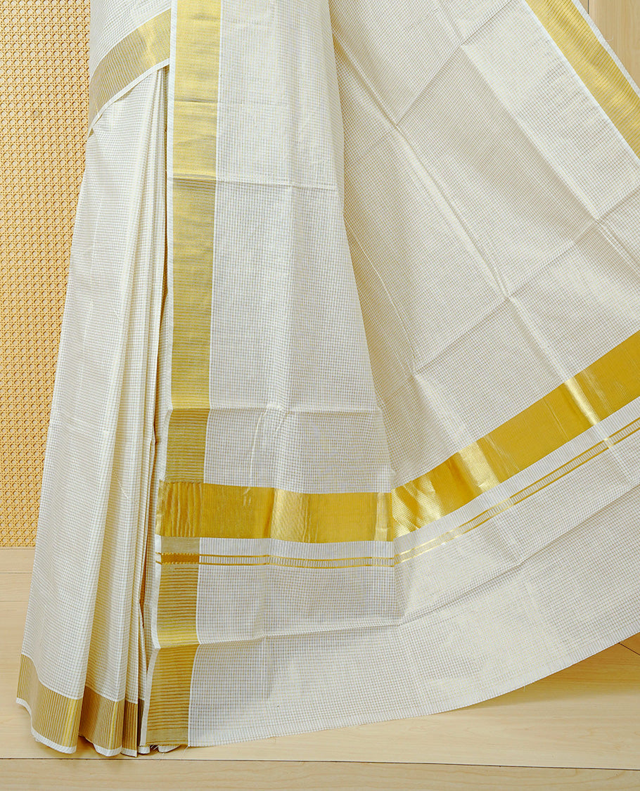 Cream Colour Cotton Kerala Saree Featuring A Golden Checks On Body, Enhanced With A Gold Zari  Border, A Traditional Gold Zari Pallu, And A Matching Blouse Piece.