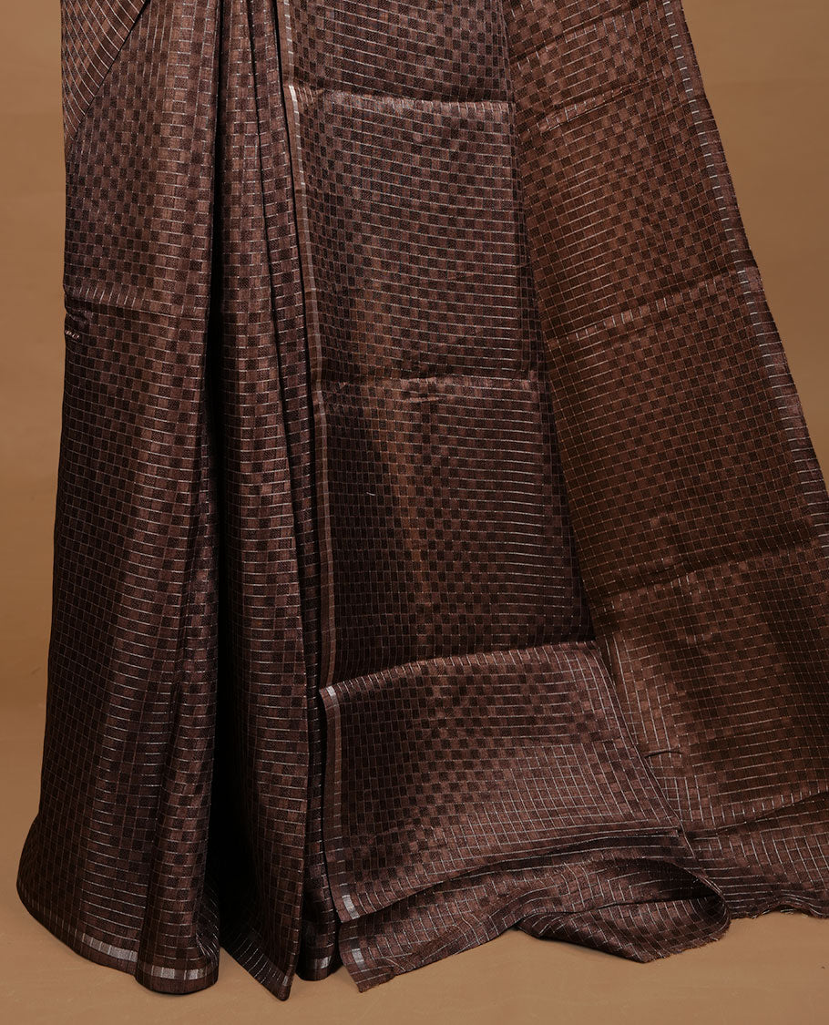 Brown colour Semi Tussar saree featuring an elegant zari fancy check pattern on the body, highlighted with a small border for a refined look. Comes without a blouse piece.