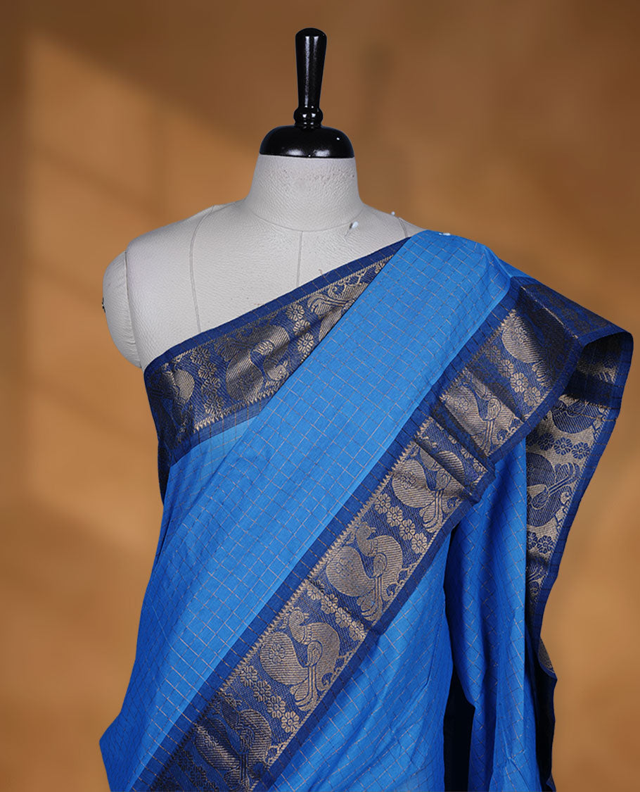 Blue colour sungudi cotton saree featuring gold zari check pattern across body, contrast Dark blue colour with gold zari peacock and floral pattern on border, without blouse piece.