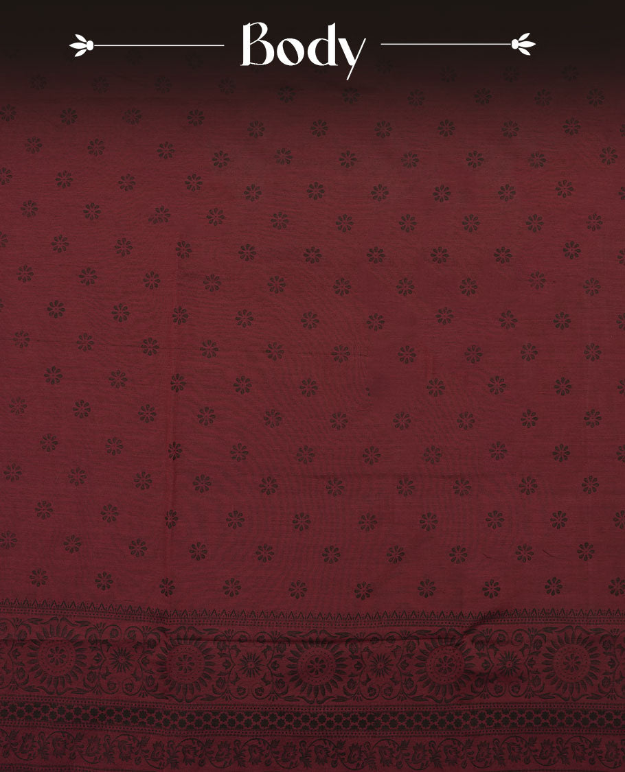 Deep maroon colour poly cotton saree with black floral butti motifs on the body, paired with a matching pallu featuring black ornate floral jaal and stripes on the border, and a coordinated all‑over black paisley printed blouse piece.