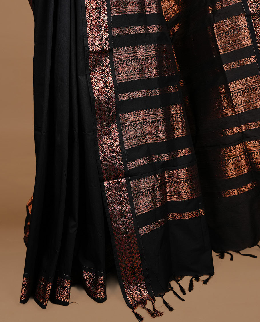 Black colour kalyani cotton saree featuring gold zari motifs on body, highlighting self colour with Antique gold zari border, paired with matching blouse piece.
