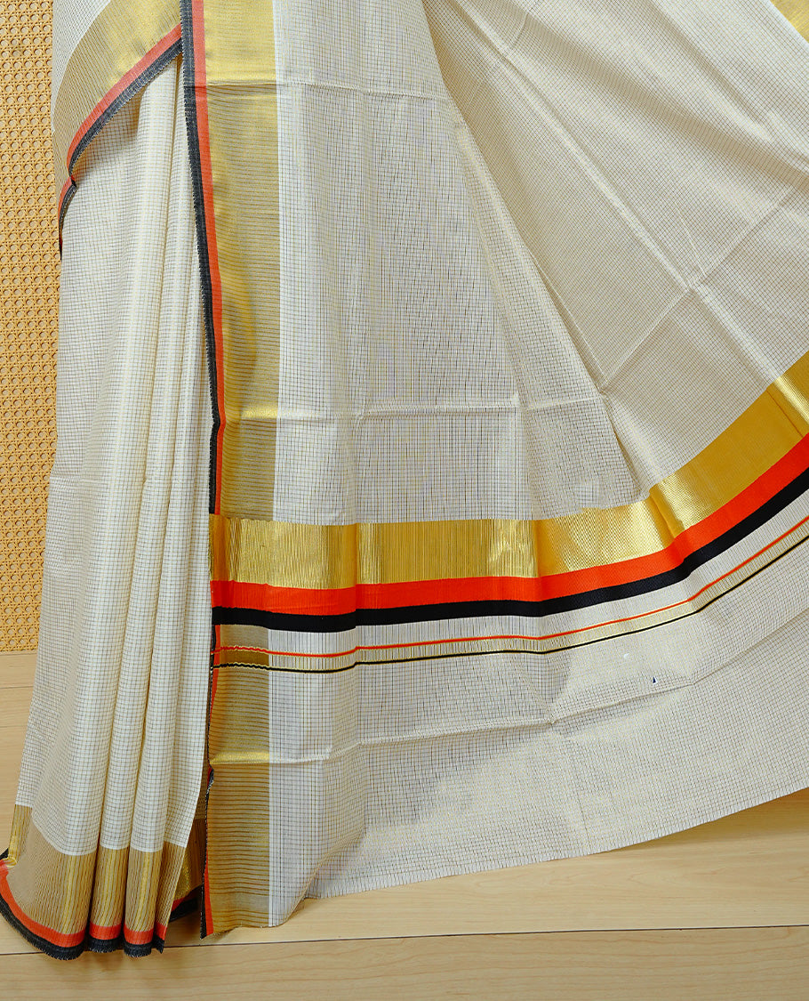 Cream colour cotton Kerala saree Featuring Gold zari Checks across the body, complemented by Classy gold zari with an orange & black Border & pallu, paired with a matching blouse piece.