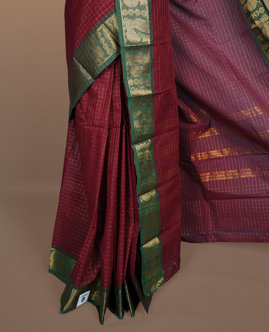 Maroon colour sungudi cotton saree featuring gold zari check pattern across body, contrast green colour with gold zari peacock and floral pattern on border, without blouse piece.