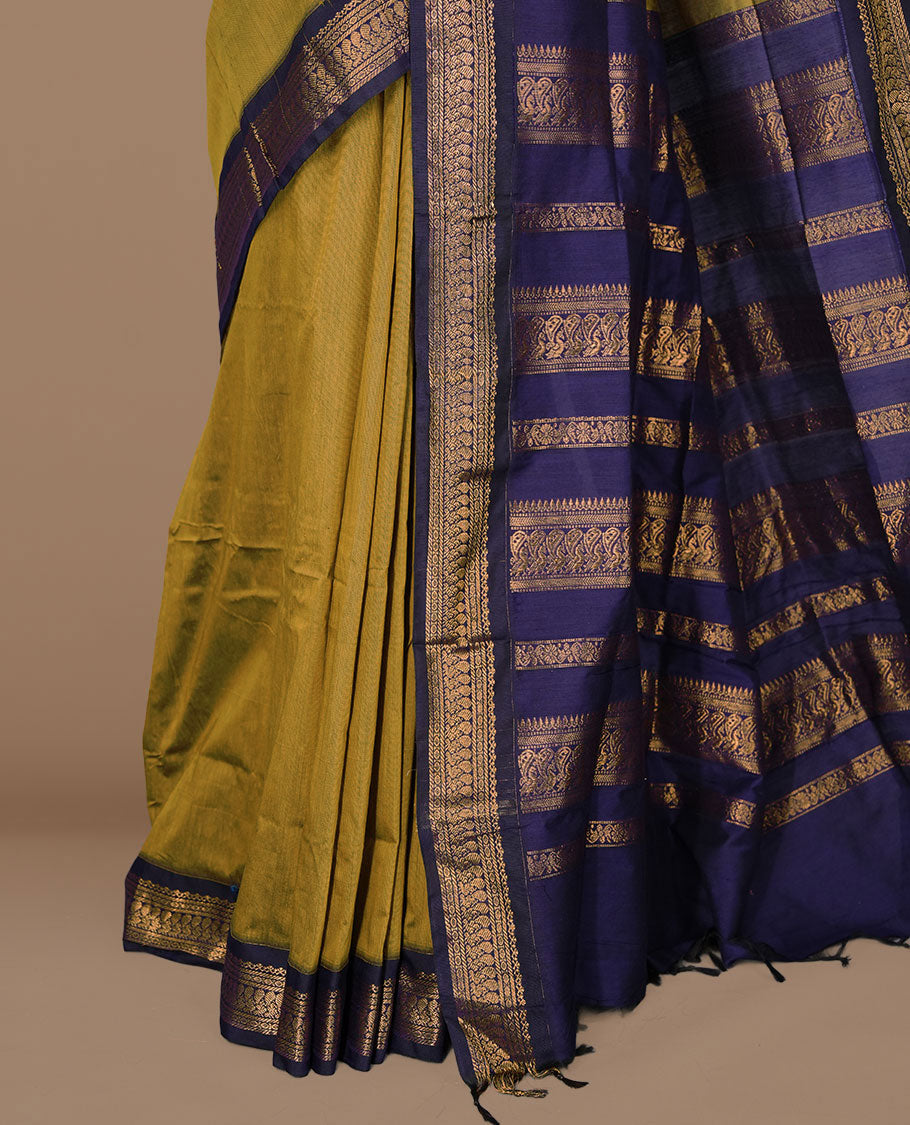Olive colour kalyani cotton saree featuring antique zari motifs on body, complemented by Dark blue colour with Antique zari border, paired with matching blouse piece.