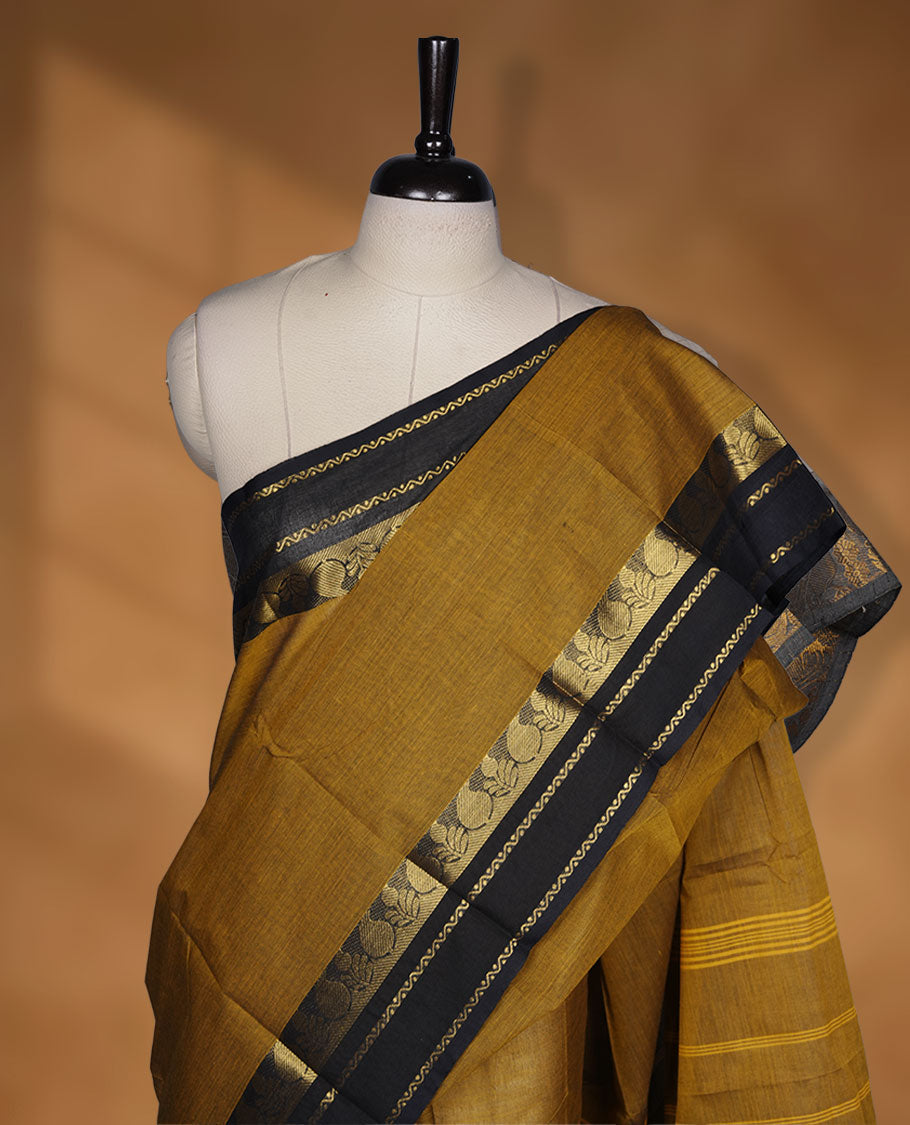 Dark mustard yellow colour chettinad cotton saree featuring plain body, paired with a black colour traditional gold zari border without blouse.
