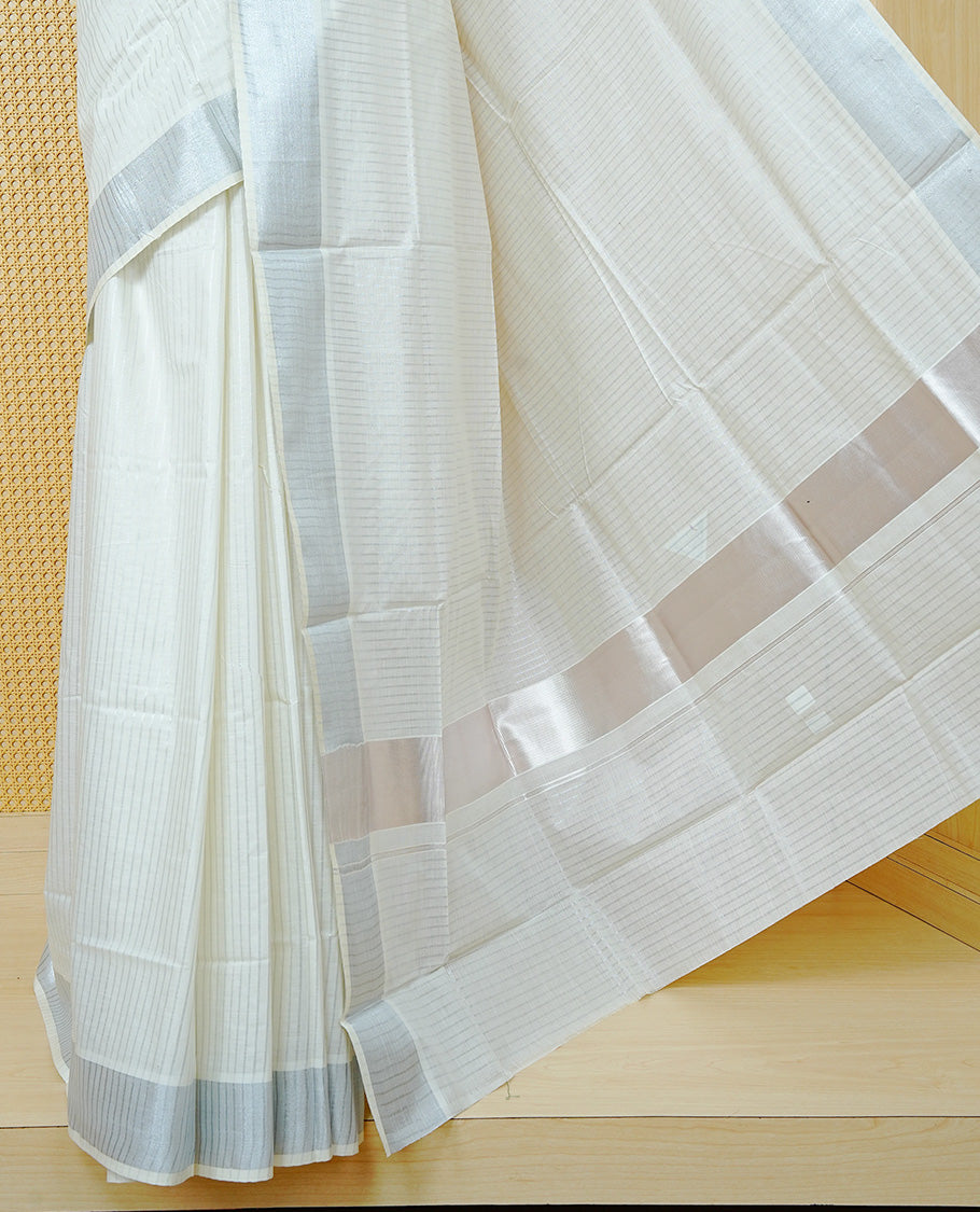 Cream colour Cotton kerala saree featuring Silver zari Stripes on body, complemented by Silver Zari Border & Rose gold zari Pallu, paired with matching blouse piece.