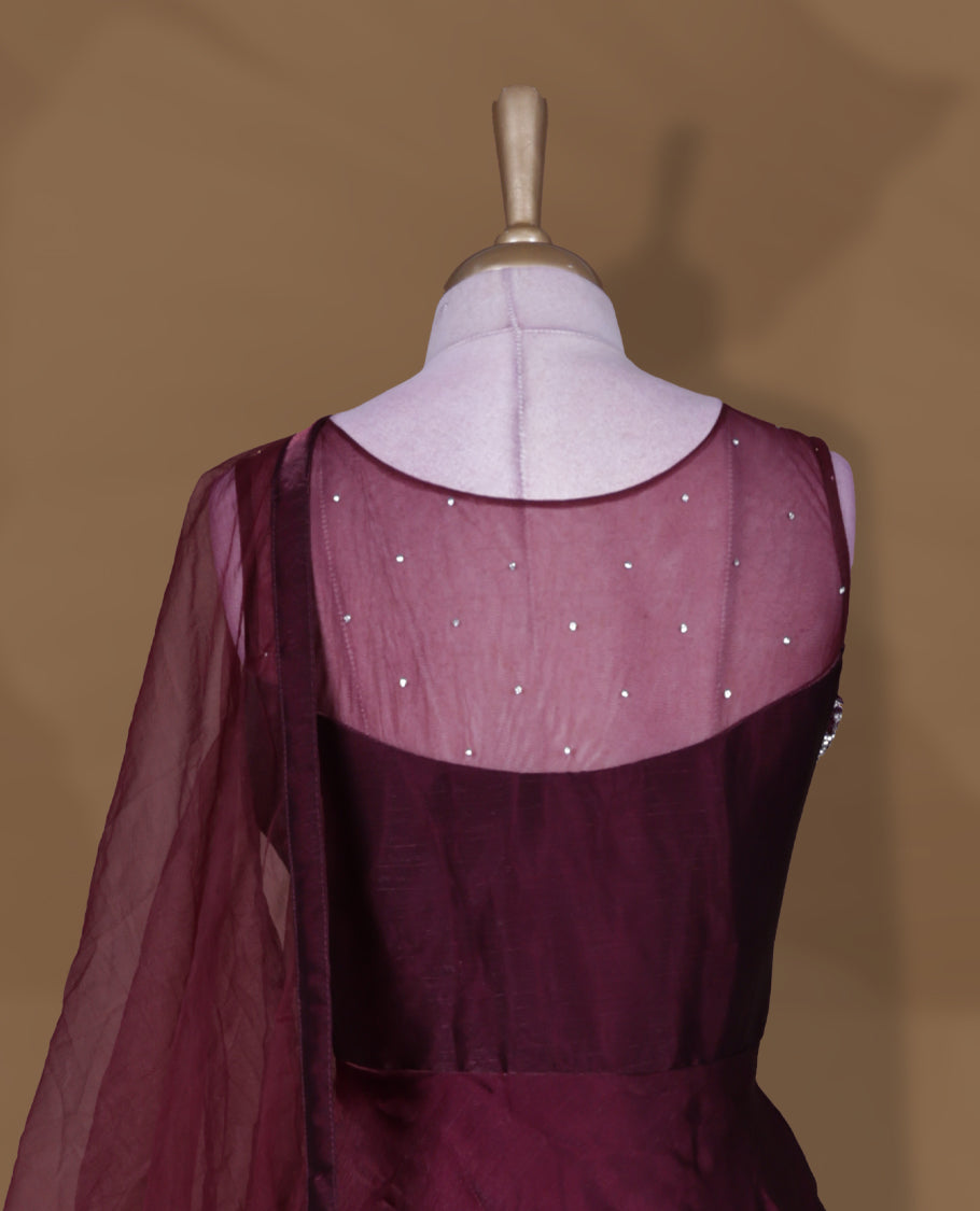 Wine colour Gown with stitched sleeveless embellished blouse featuring sheer yoke and waist detailing, matching stitched flared lehenga, and plain sheer dupatta.