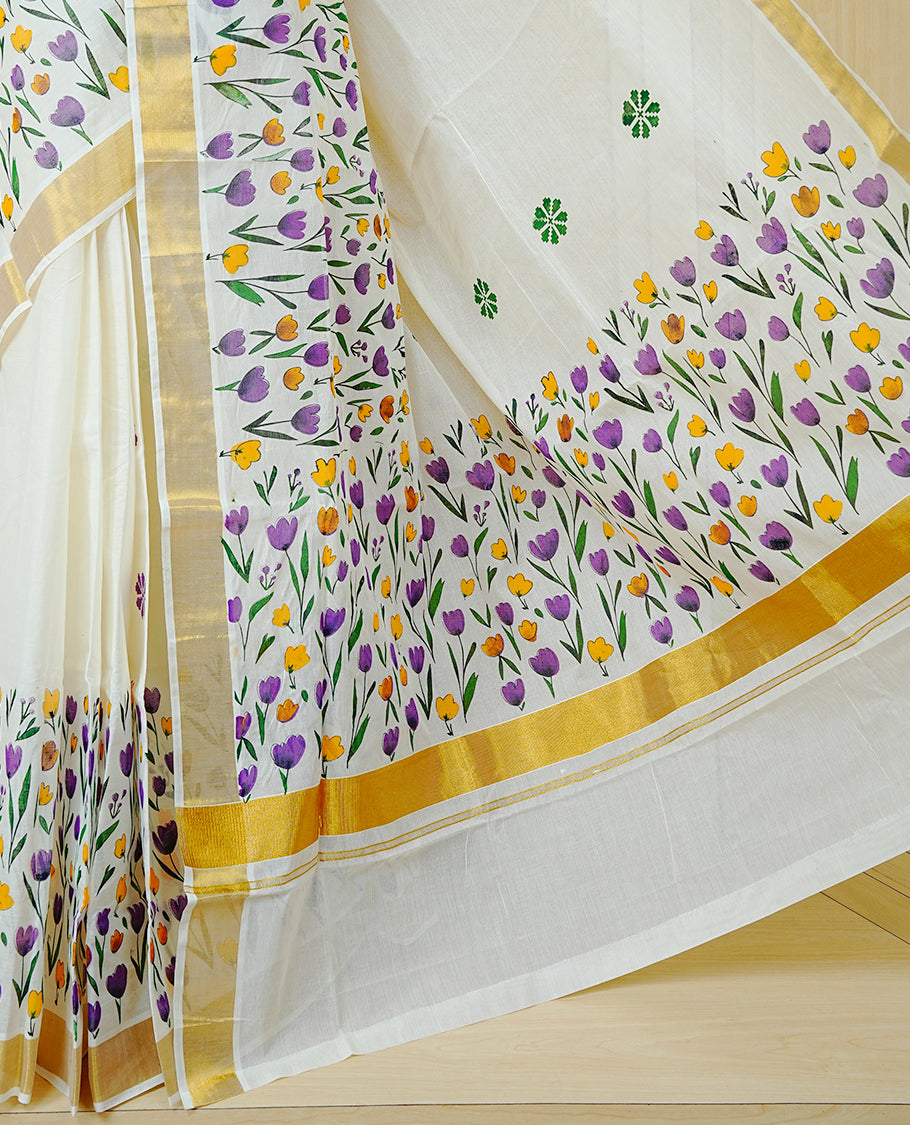 Cream Colour Cotton Kerala Saree Featuring Digital  Violet & Yellow Colour Floral Motifs On Body, With A Classic Gold Zari Border & A Gold Zari Pallu, Paired With A Matching Blouse Piece.