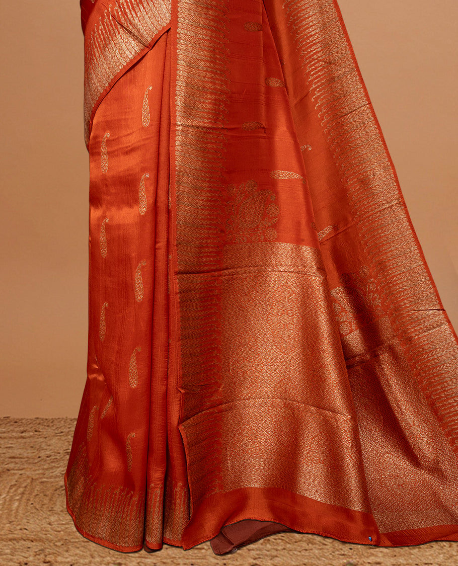 Burnt Orange colour Semi Banaras Tussar Georgette Featuring Gold zari Leaf pattern on body, Finished with Gold zari border and paired with matching blouse piece.