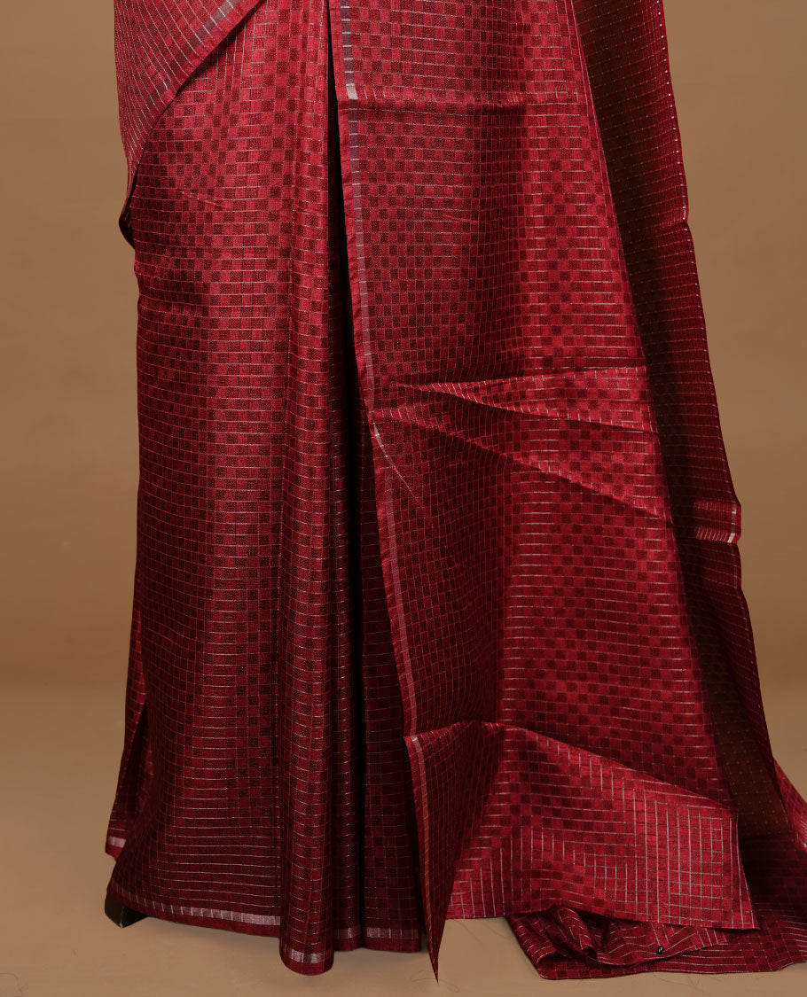 Maroon colour Semi Tussar saree featuring an elegant zari fancy check pattern on the body, highlighted with a small border for a refined look. Comes without a blouse piece.