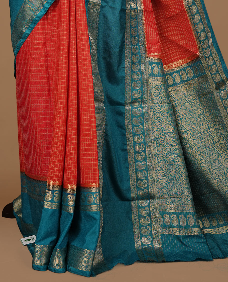 Red colour semi georgette saree featuring gold zari check pattern on body, complemented by contrast teal colour with zari border, paired with matching blouse piece.