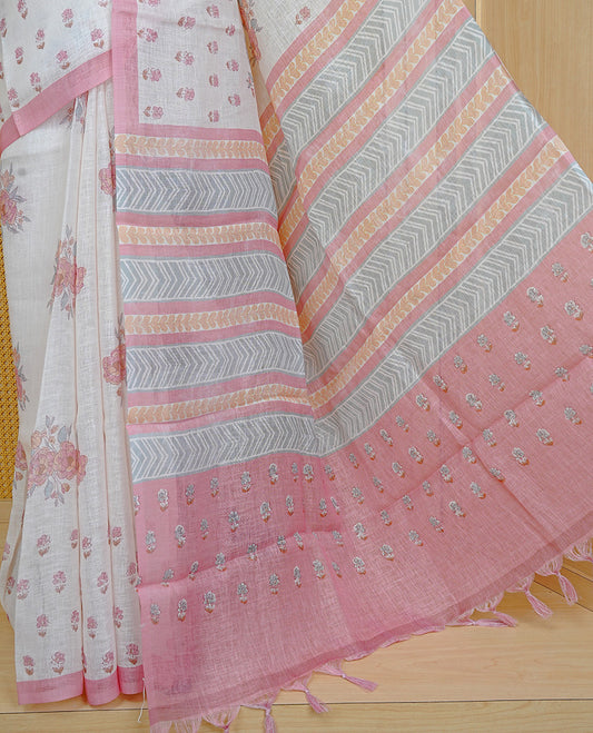Cream colour semi linen saree featuring Floral printed buttas on body, complemented by contrast Peach colour border, comes with matching blouse piece.
