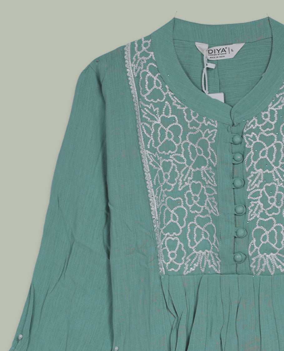 Sea green three-quarter sleeve tunic top with rounded band neckline, front floral embroidered yoke, fabric-covered button placket, and soft pleating below the yoke.