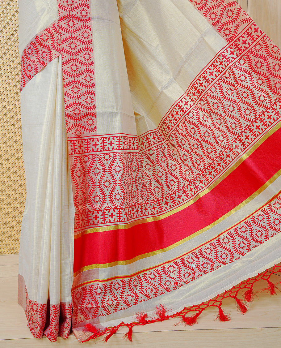 Cream Colour Tissue Kerala Saree Featuring a Plain Body, Enhanced with Red Block  Printed Borders, a Red and Gold Zari Pallu, Red Tassels, and a Matching Blouse Piece.