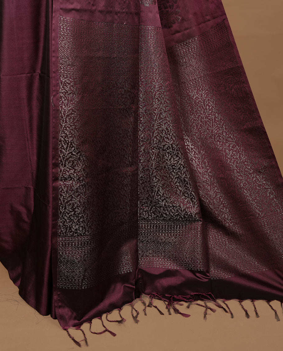 Burgundy soft silk saree features a sleek borderless design with intricate antique zari motifs, flowing into a seamless self colored pallu and a matching blouse piece.