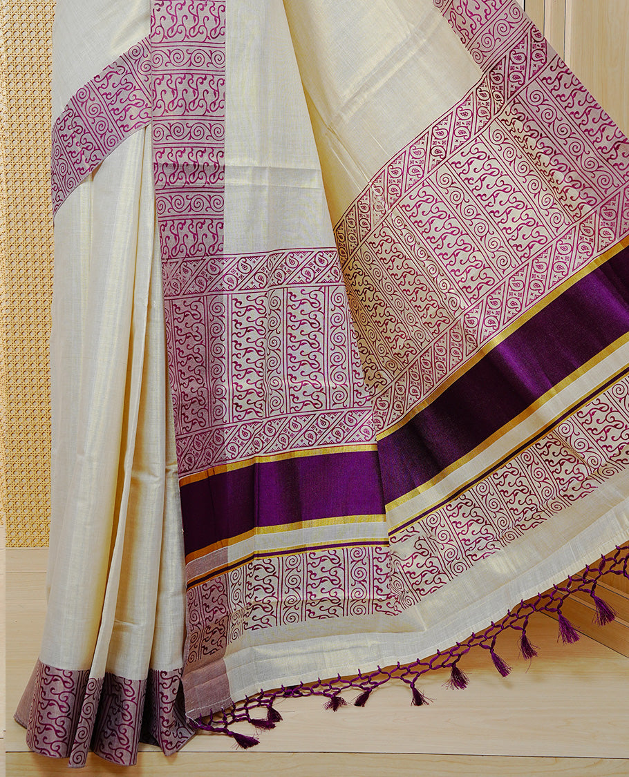 Cream Colour Tissue Kerala Saree Featuring a Plain Body, Enhanced with Violet Block  Printed Borders, a Violet and Gold Zari Pallu, Violet Tassels, and a Matching Blouse Piece.