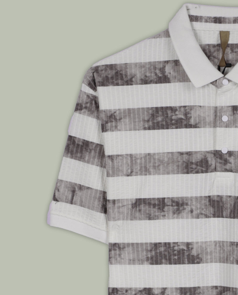 Off white and grey colour striped polo T shirt featuring a collared neck with button placket, half sleeves, and a textured fabric design, enhanced with a front chest patch that adds a trendy casual vibe.