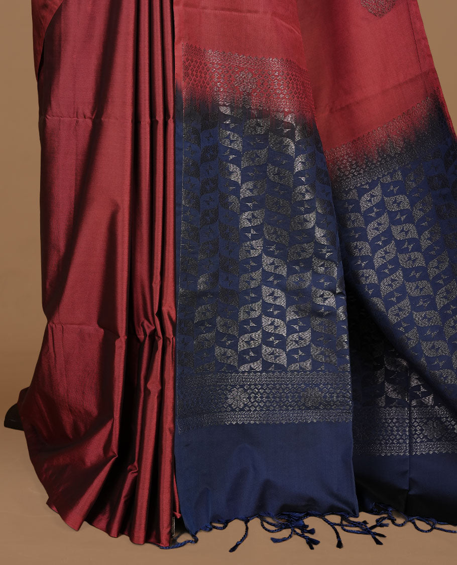 Maroon colour soft silk saree features a sleek borderless design with intricate antique zari motifs, flowing into a striking contrast blue pallu and a matching blouse piece.