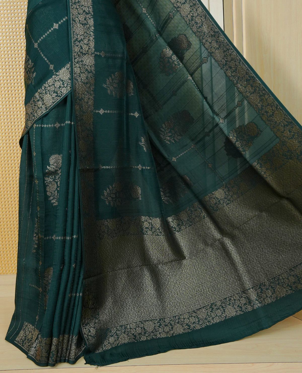 Bottle green colour semi banaras tussar georgette saree featuring gold zari floral pattern on body, finished with gold zari floral motifs on border and paired with matching blouse piece.